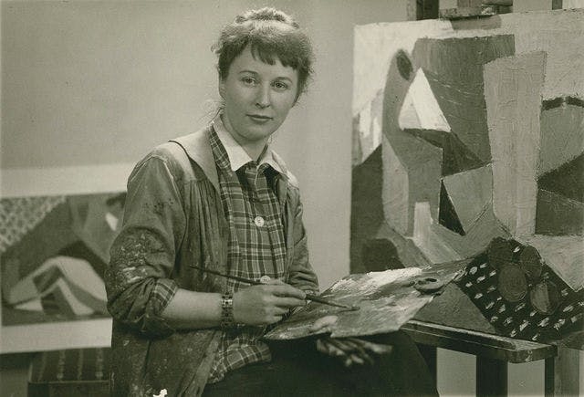 Photograph of the artist Nina Tryggvadóttir, with a painters pallet and a paint brush in her hand. 