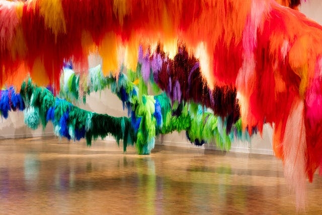Installation in the National Gallery of Iceland that shows colourful rows of hair of varied lengths. The installation is by Hrafnhildur Arnardóttir / Shoplifter.